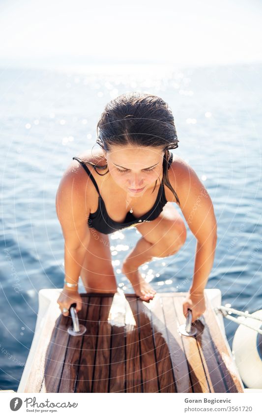Junge Frau steigt an einem sonnigen Tag auf die Yacht auf See Erwachsener allein attraktiv schön blau Holzplatte Boot Windstille Kaukasier Kreuzfahrt kreuzend