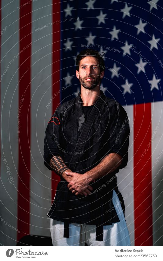 Selbstbewusster Mann in schwarzem Kimono schaut in die Kamera kämpferisch stark bärtig selbstbewusst ernst Kämpfer Porträt Erwachsener Amerikaner Fahne üben