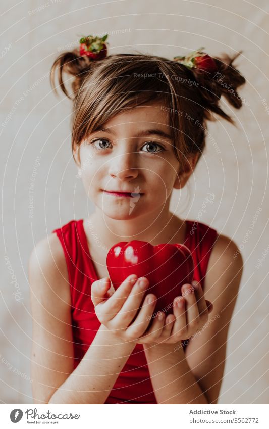 Lustiges Mädchen mit reifem Pfeffer Paprika lustig niedlich frisch Konzept Lächeln Gesundheit Gemüse Veganer Kind Haarknoten Erdbeeren wenig bezaubernd