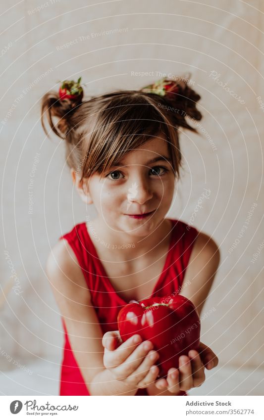 Lustiges Mädchen mit reifem Pfeffer Paprika lustig niedlich frisch Konzept Lächeln Gesundheit Gemüse Veganer Kind Haarknoten Erdbeeren wenig bezaubernd