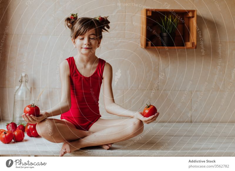 Kleines Mädchen meditiert mit Tomaten meditieren Küche Konzept Lotus-Pose Yoga Gesundheit rot hell niedlich Barfuß Body heimwärts sitzen Abfertigungsschalter