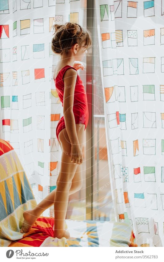 Kleines Mädchen schaut aus dem Fenster heimwärts Sofa Gardine ruhen stehen Body farbenfroh hell gemütlich Lifestyle Raum Komfort Appartement