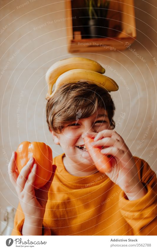 Fröhlicher Teenager spielt mit Obst und Gemüse spielen Küche Kind Konzept heimwärts Übergewicht Lächeln Diät Lebensmittel Gesundheit Junge Paprika Möhre Banane