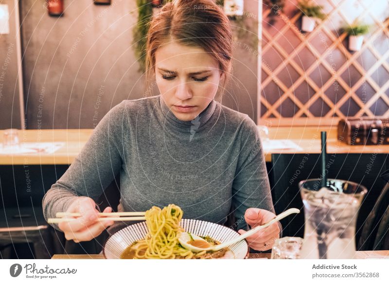 Junge Frau isst Ramen im Cafe essen Café Tradition Japanisch jung Löffel Essstäbchen Schalen & Schüsseln Speise Tisch geschmackvoll Küche Lifestyle Restaurant