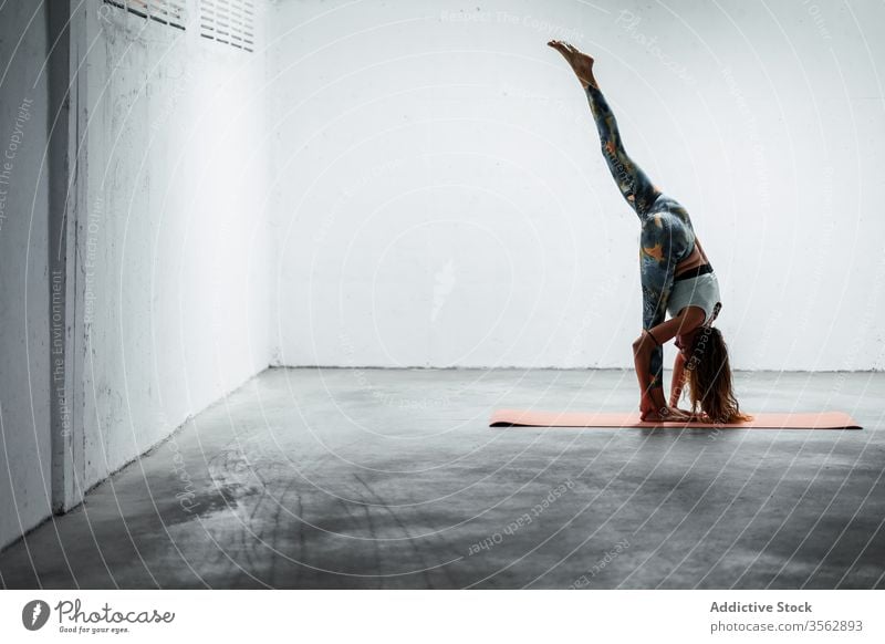 Ruhige Frau beim Stehen auf der Matte gespalten Yoga Stehende Teilung Split üben beweglich Unterlage Gleichgewicht ruhig Harmonie Windstille Pose schlanke Asana
