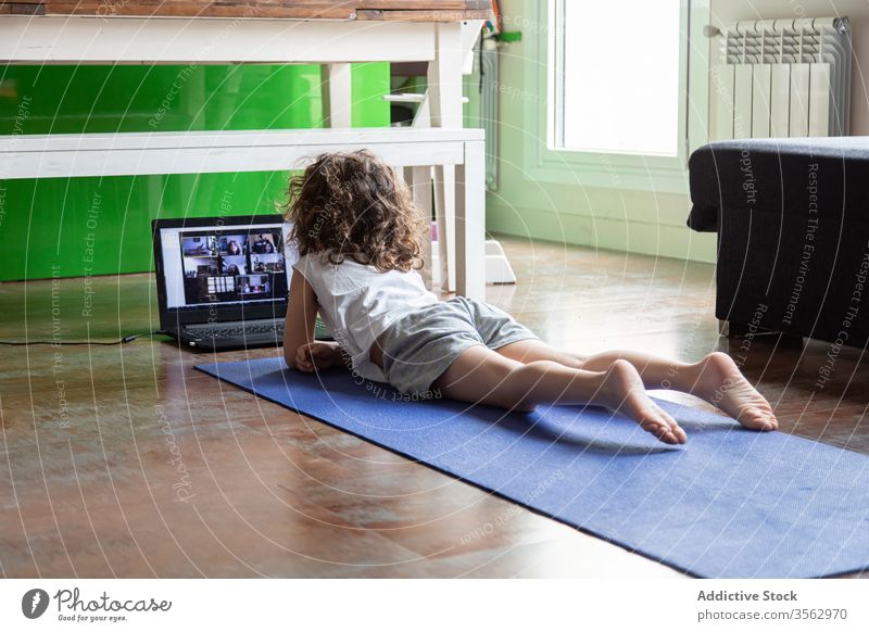 Kleines Mädchen lernt zu Hause online Yoga Kind Laptop üben heimwärts zuschauen Video Tutorial lernen Pose Gerät Apparatur Internet benutzend Unterlage wenig
