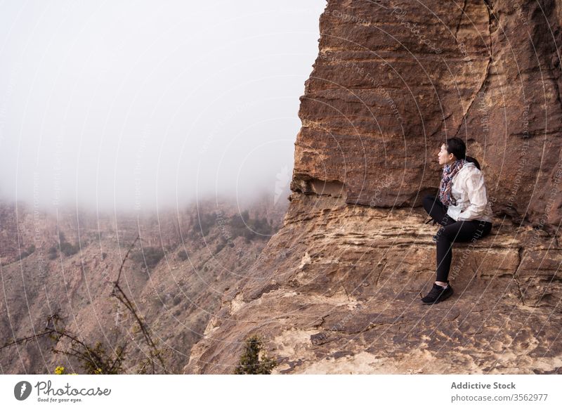 Ethnischer Reisender auf Fels sitzend Frau reisen Felsen Berge u. Gebirge Nebel erkunden ethnisch Natur lässig Klippe asiatisch Abenteuer Landschaft Ausflug