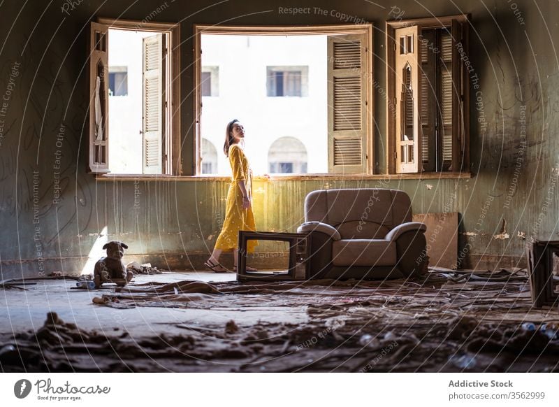 Frau steht im Wohnzimmer eines verlassenen Hauses Fenster Raum Verlassen Unbewohnt alt schäbig unordentlich Appartement wohnbedingt jung ethnisch Saudi-Arabien