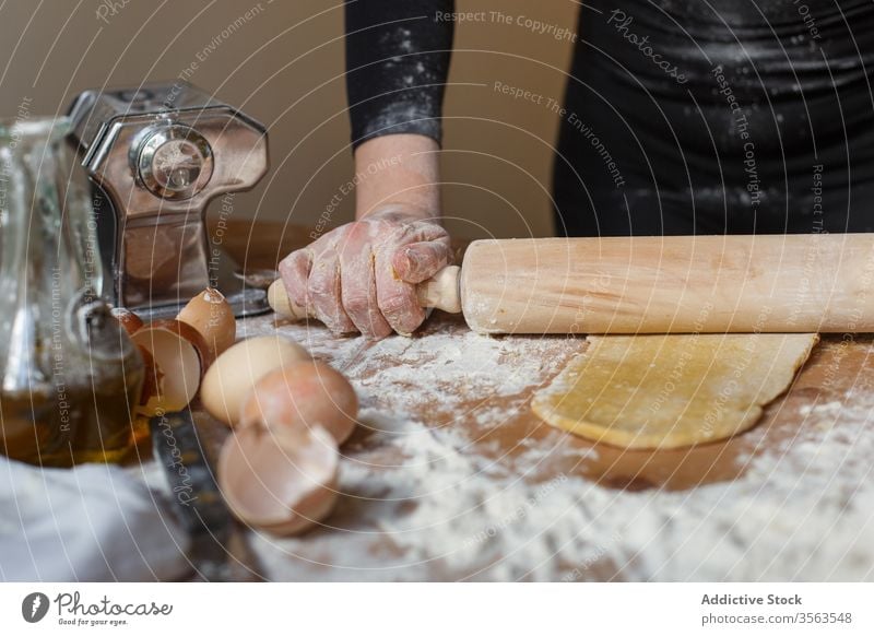Crop Lady Teigrolle mit Nudelholz auf dem Tisch Koch Teigwaren Frau rollen Gebäck elastisch Mehl Ei Küchengeräte Kannen Eierschale Glas vorbereiten Bestandteil