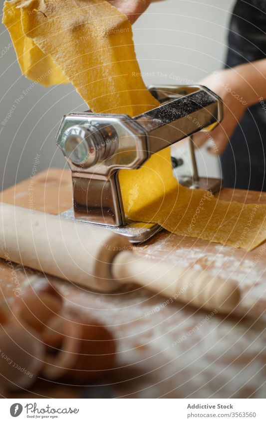 Anonyme Köchin rollt Teig aus, während sie die Nudelmaschine benutzt Frau Koch Spätzle rollen Maschine Teigwaren Gebäck elastisch Mehl Vorrichtung Küchengeräte