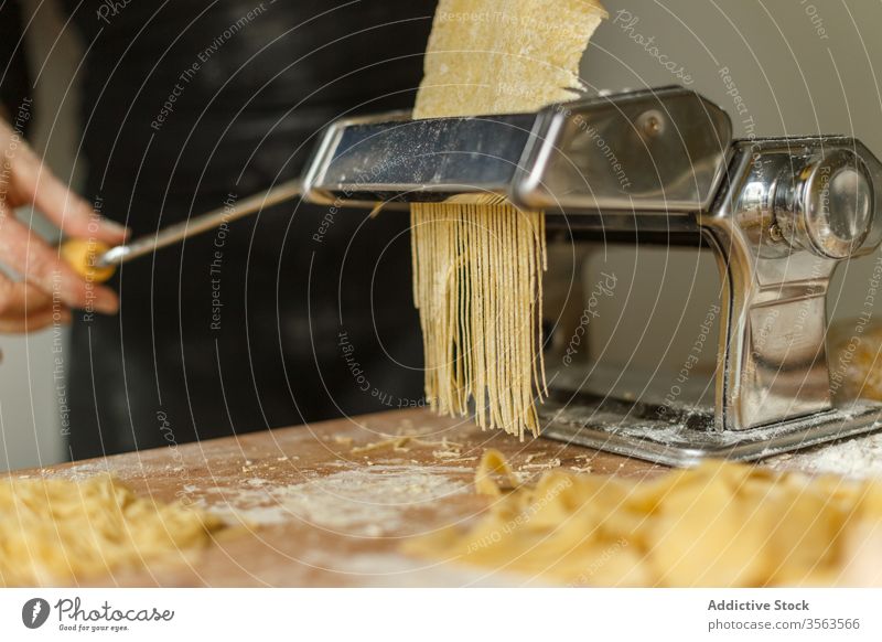 Gesichtslose Köchin schneidet Gebäck mit einer Nudelmaschine Frau Maschine Spätzle rollen Streifen geschnitten dünn benutzend roh Form Teigwaren Gerät Koch Mehl