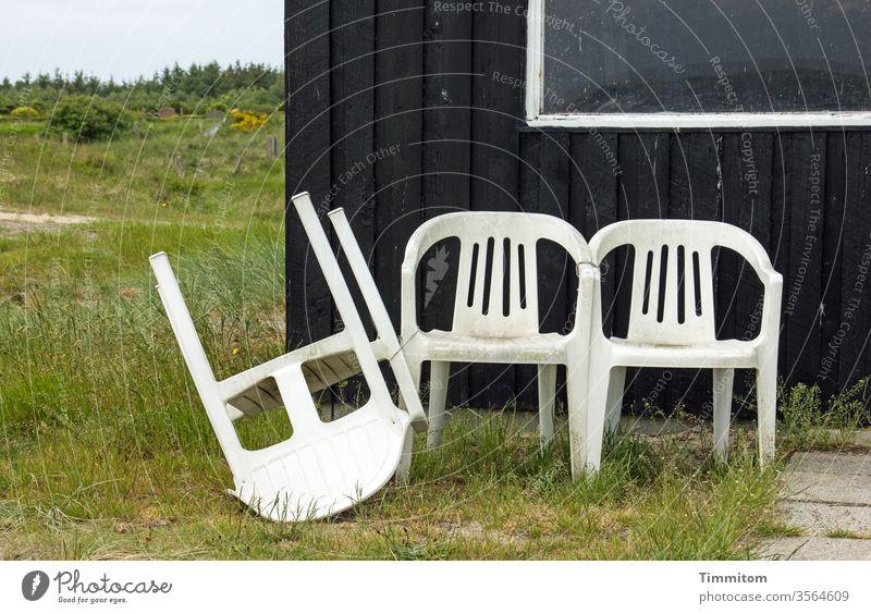 Unfrieden bei den Sitzgelegenheiten Stühle Kunststoff drei umgeworfen Haus Hütte Fenster Holz zusammengebunden Schnur Gras Menschenleer Farbfoto Aussicht