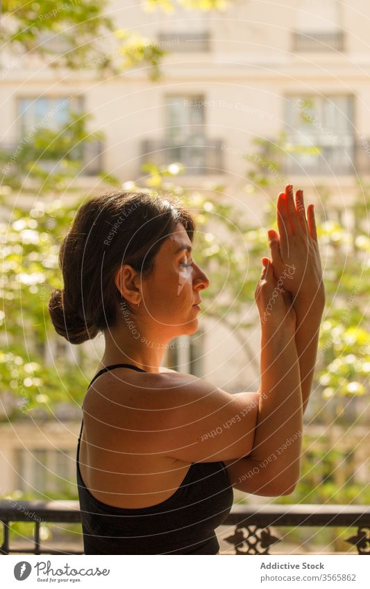 Ruhiges weibliches Stehen in Adlerstellung während der Yogapraxis im Sommer Frau heimwärts üben meditieren Adler-Pose Asana Balkon Windstille Frieden