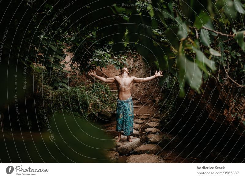 Unbekannter Mann in traditioneller Hose meditiert im Wald meditieren Sprit Natur Tradition ethnisch Baum Garten ohne Hemd männlich muskulös nackter Torso Barfuß