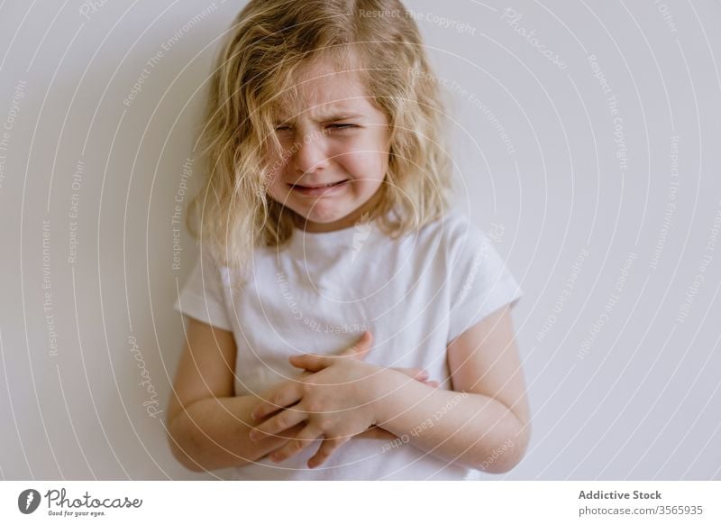 Kleines weinendes Mädchen im Studio unanständig wenig Kind verschränkte Arme jammern lässig traurig Stirnrunzeln enttäuschen Kindheit Gesichtsausdruck