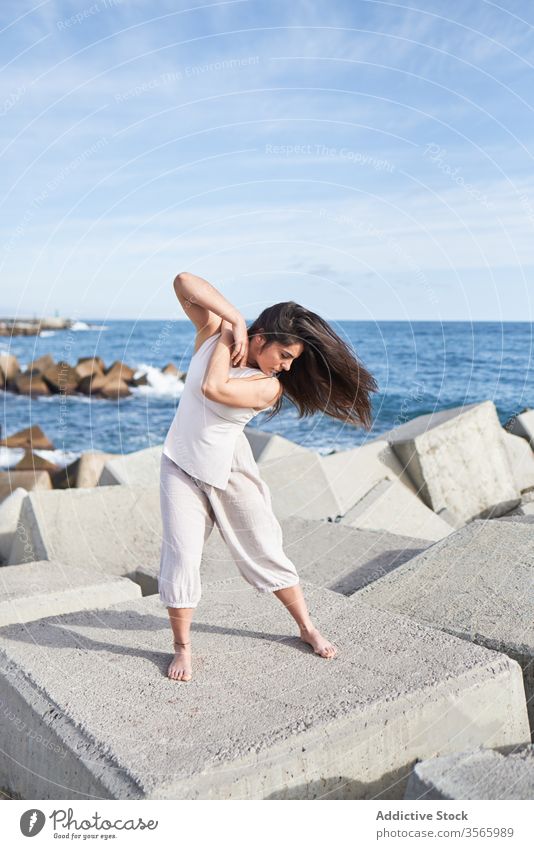 Moderne Frau steht auf Betonblock des Wellenbrechers MEER Tanzen sinnlich Kraft Harmonie Küste Zeitgenosse Konzept Stein Konstruktion Energie physisch jung Pose