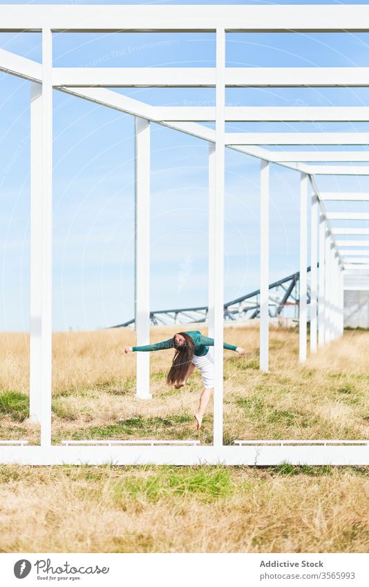 Junge Frau in der Nähe einer Metallkonstruktion auf dem Land Feld Landschaft Tanzen fallen Konstruktion Wegbiegung Geometrie Fliege modern Straße Kunst Natur