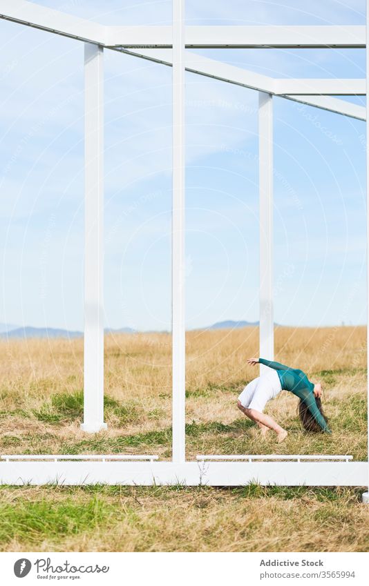 Junge Frau in der Nähe einer Metallkonstruktion auf dem Land Feld Landschaft Tanzen fallen Konstruktion Wegbiegung Geometrie Fliege modern Straße Kunst Natur