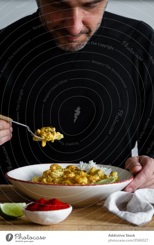 Mann isst leckeres Curry aus Pilzen und Garnelen essen geschmackvoll Würzig Reis Granele Indisches Essen männlich Küche Kalk Scheibe lässig anhaben Tisch sitzen