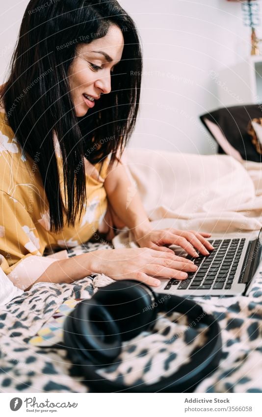Frau mit Laptop und Kopfhörern auf dem Bett Musik Kälte Glück genießen Komfort räkeln Schlafzimmer sich[Akk] entspannen Lifestyle ruhen Apparatur Gerät