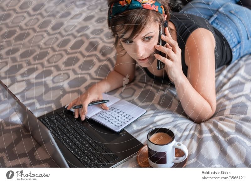 Junge Freiberuflerin spricht mit Smartphone im Bett freiberuflich reden Frau selbständig sprechen Notebook Laptop benutzend jung Unternehmer Schüler lernen