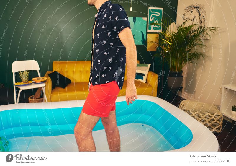 Mann im aufblasbaren Pool während Hausparty heimwärts Party zu Hause bleiben Sommer Appartement kreativ Selbstisolierung Spaß haben Wasser männlich Shorts Hemd