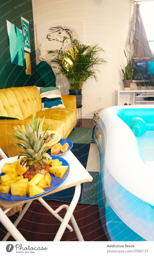 Innenraum des Wohnzimmers mit aufblasbarem Pool Party tropisch zu Hause bleiben Selbstisolierung Frucht Innenbereich soziale Distanzierung Appartement heimwärts