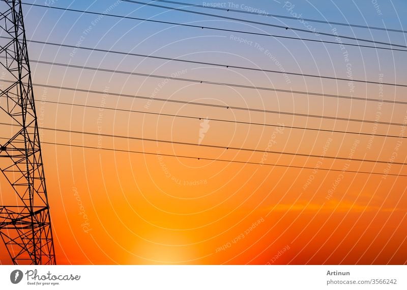 Silhouette eines Hochspannungsmastes und eines elektrischen Kabels mit einem orangefarbenen Himmel. Strommasten bei Sonnenuntergang. Strom- und Energiekonzept. Hochspannungsgittermast mit Drahtkabel an der Verteilerstation.