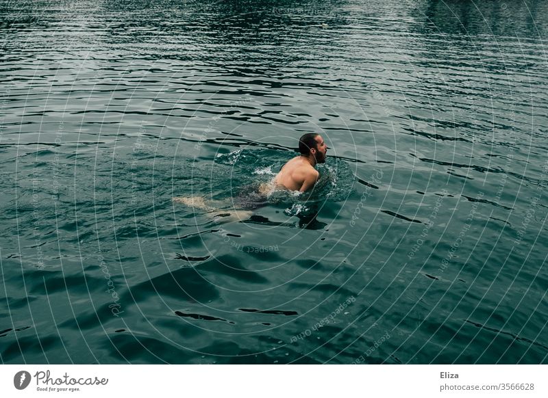 Ein Mann beim Schwimmen im kalten Wasser kühl Schwimmer Meer See baden blau Sommer Schwimmen & Baden braunhaarig Urlaub bedrohlich Luft holen Gefahr dunkel