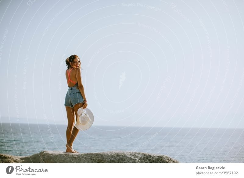 Junge Frau im Bikini auf Felsen am Meer stehend Erwachsener attraktiv Strand schön blau brünett Kaukasier Küste Tag Griechenland Behaarung Feiertag Freizeit