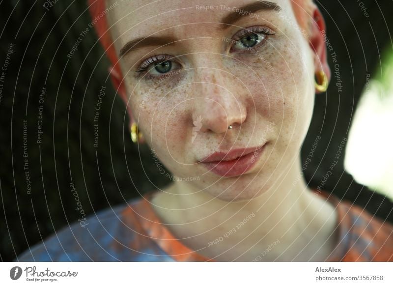 Portrait einer jungen Frau vor einem Baum 18-25 Jahre schön Schlank Sommersprossen rothaarig schmuck Piercing Tätowierung Gesicht hellhäutig kurzhaarig weiß