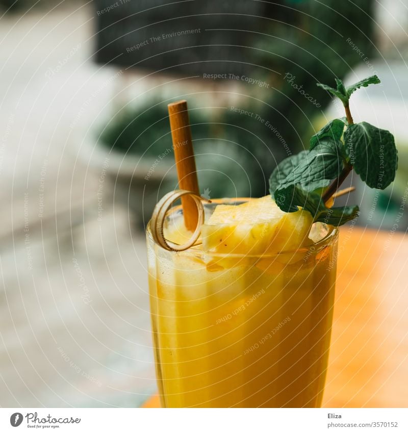Gesunder frischer Ananassaft Smoothie mit frischer Minze Saft gesund Mango gelb lecker gepresst Glas Strohhalm draußen Getränk erfrischend fruchtig Cocktail