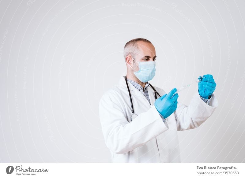 arztmann mit einer spritze und einem fläschchen. mit schutzmaske und handschuhen während der coronavirus covid 2019 pandemie. Gesundheitsversorgung und medizinisches Konzept