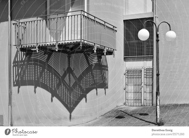 Balkon und Straßenlaterne werfen Schatten Gebäudeteil Haus Mauer Schwarz-Weiß-Foto Außenaufnahme Menschenleer Sonne Tag Architektur Fenster Mittagszeit