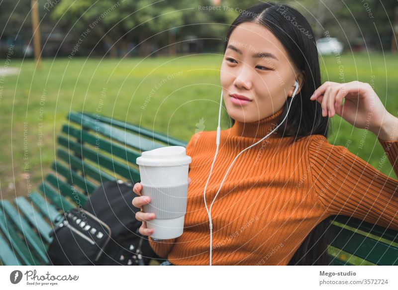 Asiatische Frau, die Musik hört. Kaffee Mädchen asiatisch Park im Freien jung schön Kopfhörer zuhören Person außerhalb Lifestyle Chinesisch Großstadt grün