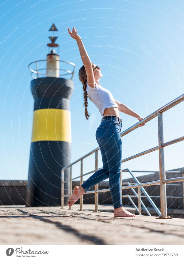 Zufriedene Frau mit erhobenem Arm am Wasser Hafengebiet Inhalt verträumt Stauanlage Leuchtturm genießen Strandpromenade sich[Akk] entspannen Sommer reisen