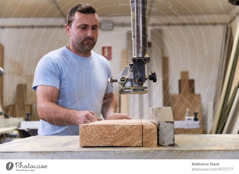Aufmerksamer Erwachsener sägt Holz im Arbeitsraum Mann Säge Maschine Nutzholz Schreinerei geschnitten Zimmerer Schiffsplanken Werkstatt Tischler Gerät