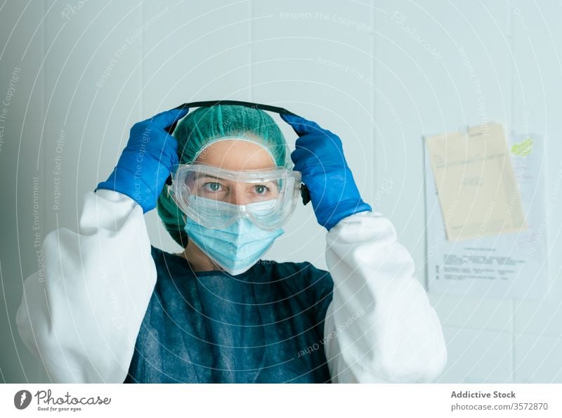 Ärztin mit Schutzmaske und Schutzbrille Mundschutz medizinisch behüten Coronavirus COVID Frau Krankenpfleger Arzt Sicherheit Sanitäter anhaben angezogen Uniform