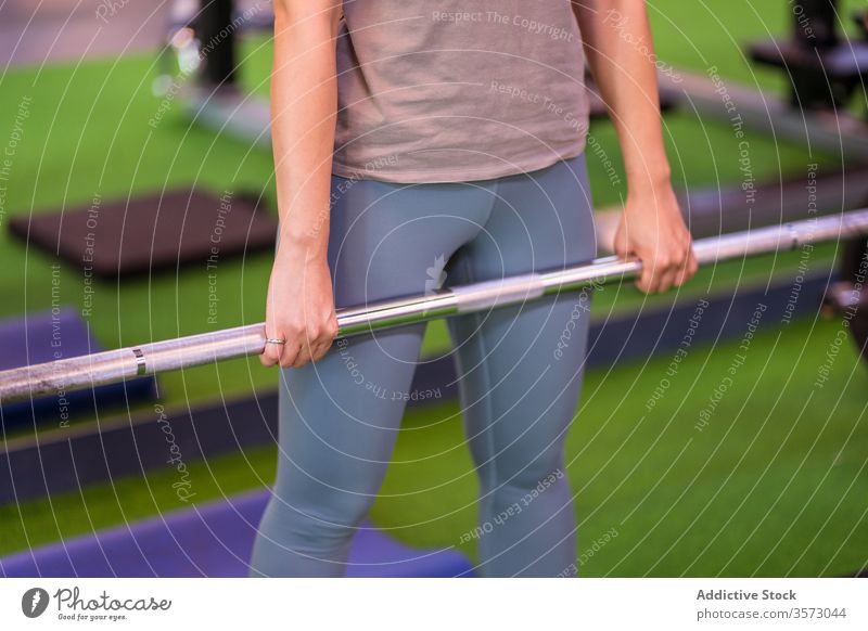 Kräftige Sportlerin macht Kniebeuge mit Langhantel in moderner Turnhalle Frau Curl-Hantel Training aktive Kleidung Maschine Gerät Fokus atmen stark Athlet