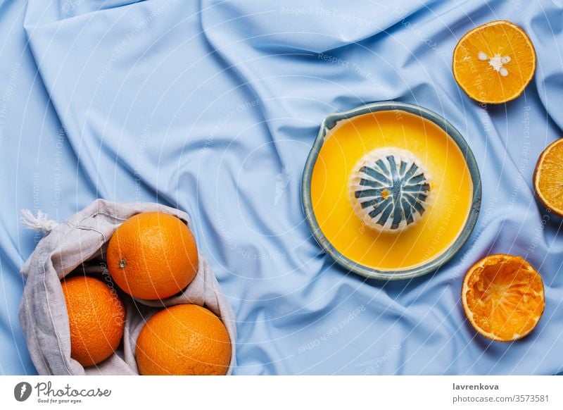 Flatlay aus geschnittenen Orangen und Keramik-Handpresse auf blauem Vorhang Zitrusfrüchte lecker Lebensmittel frisch Frucht Gesundheit Bestandteil Entsafter