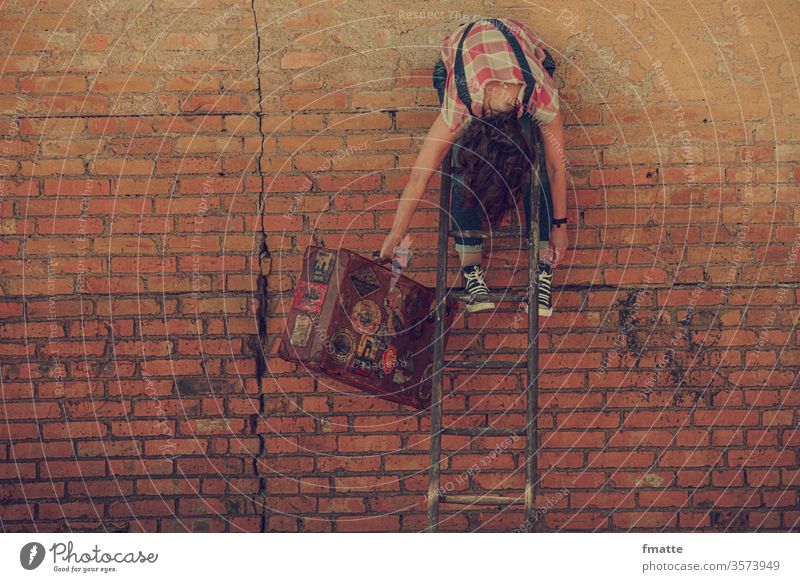 Frau hängt über einer Leiter mit Reisekoffer reise reisekoffer warten hängen lassen Leitersprosse urlaub