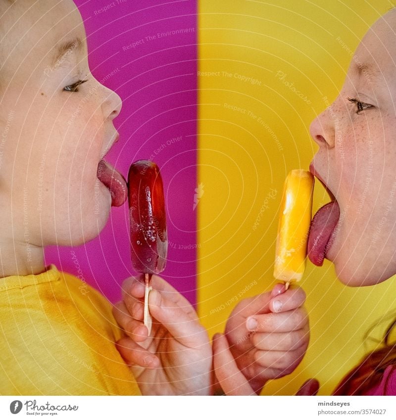 Zwei Kinder lecken Eis am Stil Mädchen Kindheit Kontrast pink gelb eis am stiel Sommer Speiseeis Frucht Lebensmittel gefroren Geschwister essen naschen Farbfoto