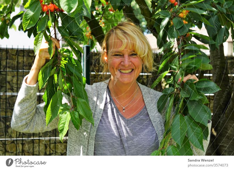 Frau unterm Kirschbaum Baum Kirschen Ernte Blonde Haare Fröhlichkeit Lachen Sonnenschein schönes Wetter Freizeit Garten Obst