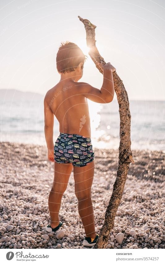 Kleiner Junge mit einem großen Stock am Strand bei Sonnenuntergang Abenteuer Baby Rücken Hintergrund schön heiter Kind Kindheit Kinder Küste erkundend Familie
