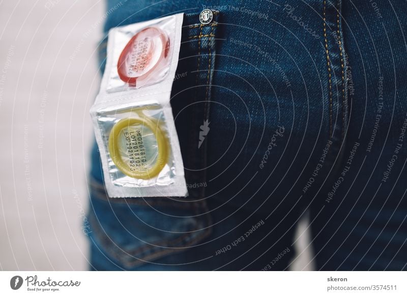 junger Typ in Jeans bereitet sich auf ein romantisches Date vor - gibt ein farbiges Kondom in die Gesäßtasche seiner Jeans. Körperteil: männlicher Arsch. Konzept: Schutz vor sexuell übertragbaren Krankheiten