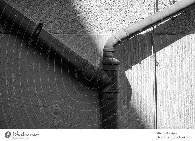 Wasserrohre an einer Hauswand hauswand Wand Menschenleer Fassade Gebäude Detailaufnahme grau Schwarzweißfoto Schatten