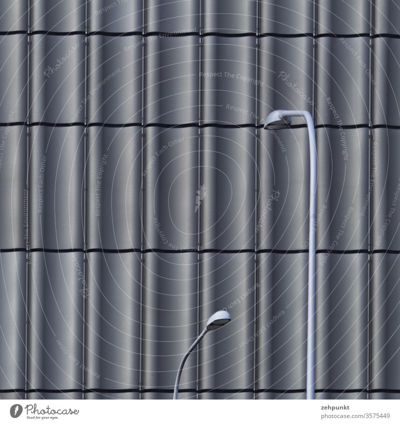 Zwei graue Strassenlaternen biegen sich vor dem gewellten, grauen Fassadenraster (Ausschnitt) der ZHdK Fassadenverkleidung Raster Straßenlaterne orthogonal
