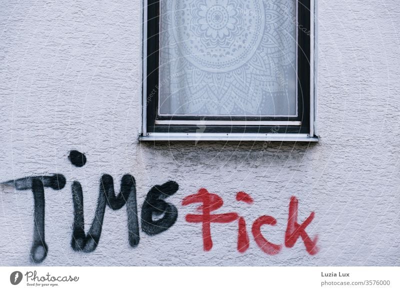 Time Fick: Graffiti schwarz rot unter einem Fenster mit auffälliger Spitzengardine Fassade Rauputz weiß Stadt hässlich urban Außenaufnahme Menschenleer Farbfoto