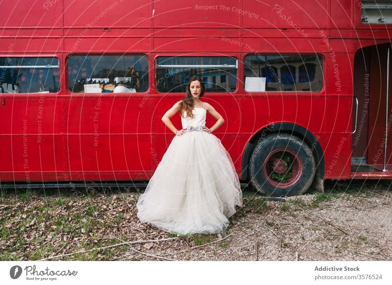 Seriöse Braut steht neben rotem Doppeldeckerbus Jungvermählter roter Bus Hochzeit Holz Brautkleid retro ernst emotionslos Frau elegant Wald Hochzeitstag