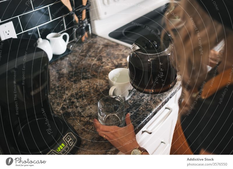 Anonyme Hausfrau schüttet in Küche Kaffee in Tasse eingießen Kaffeekanne Morgen brauen Aroma vorbereiten lecker heiß frisch trinken Frühstück geschmackvoll